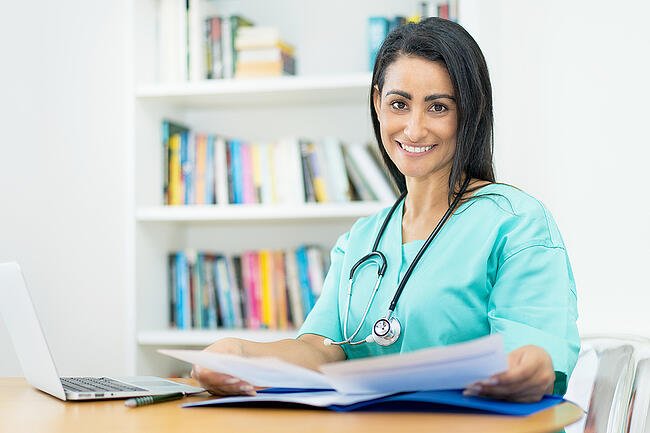 Smiling dark haired nurse creating a nursing schedule.