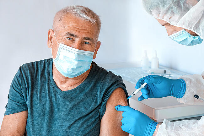 Elderly man getting a vaccine at a vaccine clinic.