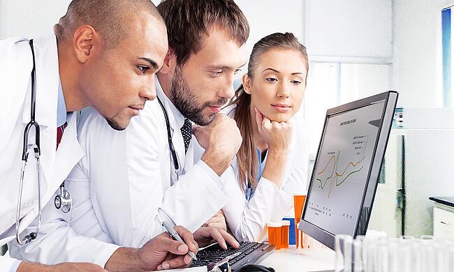 Medical team looking at reports on a laptop computer.