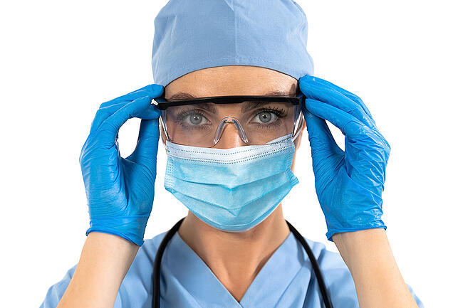 Female nurse wearing medical gloves, surgical mask, and goggles.
