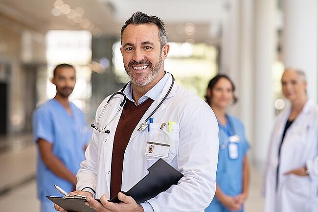 Smiling doctor standing in front of hospital staff.