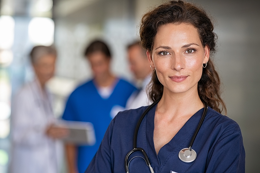 Portrait of proud female nurse with stethoscope around neck at medical clinic.